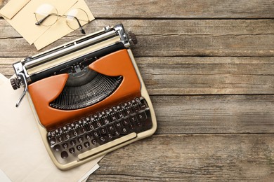 Photo of Vintage typewriter, glasses, envelopes and sheets of paper on wooden table, flat lay. Space for text