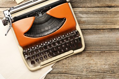 Photo of Vintage typewriter and sheets of paper on wooden table, top view. Space for text