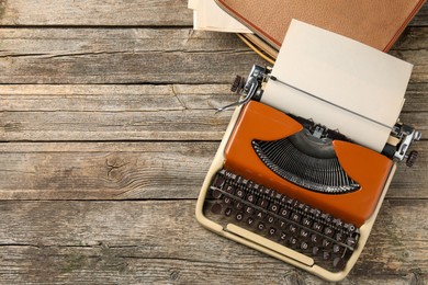 Photo of Vintage typewriter with sheet of paper and bag on wooden table, top view. Space for text