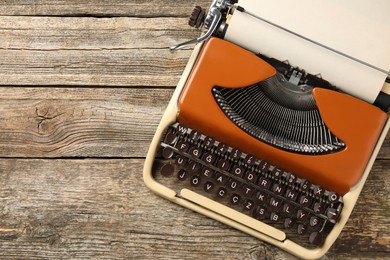 Photo of Vintage typewriter with sheet of paper on wooden table, top view. Space for text