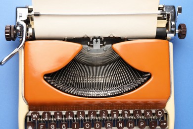 Photo of Vintage typewriter with sheet of paper on blue background, top view