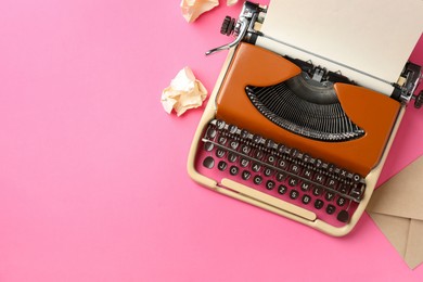 Photo of Vintage typewriter, crumpled paper and envelope on pink background, flat lay. Space for text