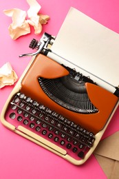 Photo of Vintage typewriter, crumpled paper and envelope on pink background, flat lay