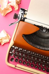 Photo of Vintage typewriter and crumpled paper on pink background, top view