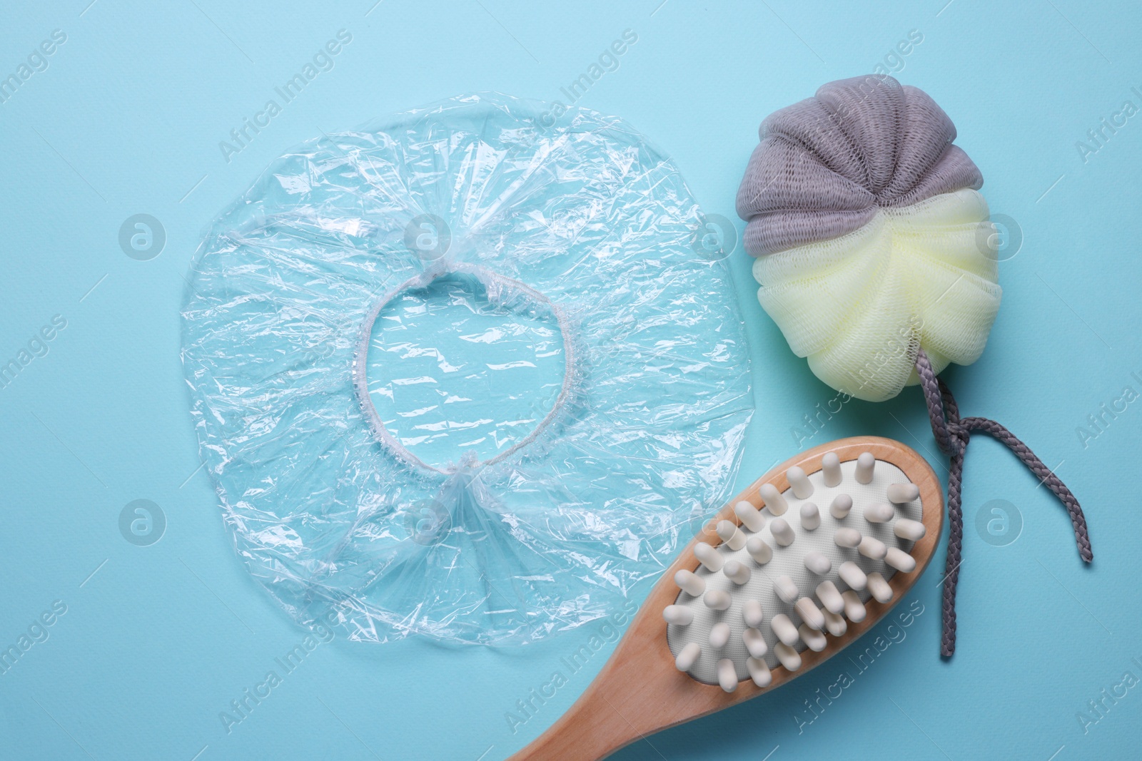 Photo of Shower cap and bath accessories on light blue background, flat lay