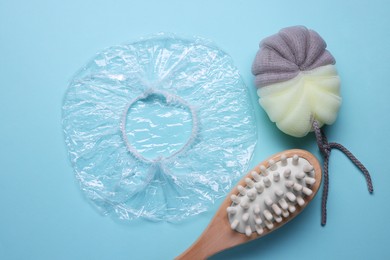 Photo of Shower cap and bath accessories on light blue background, flat lay