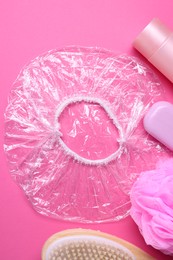 Photo of Shower cap and bath accessories on pink background, flat lay