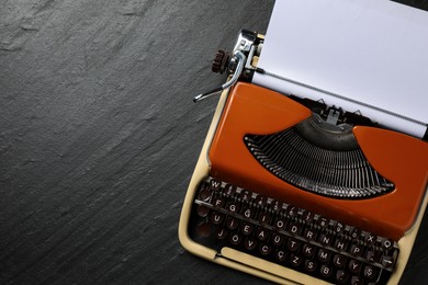 Photo of Vintage typewriter with sheet of paper on black background, top view. Space for text