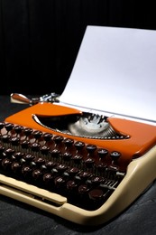 Photo of Vintage typewriter with sheet of paper on black background, closeup