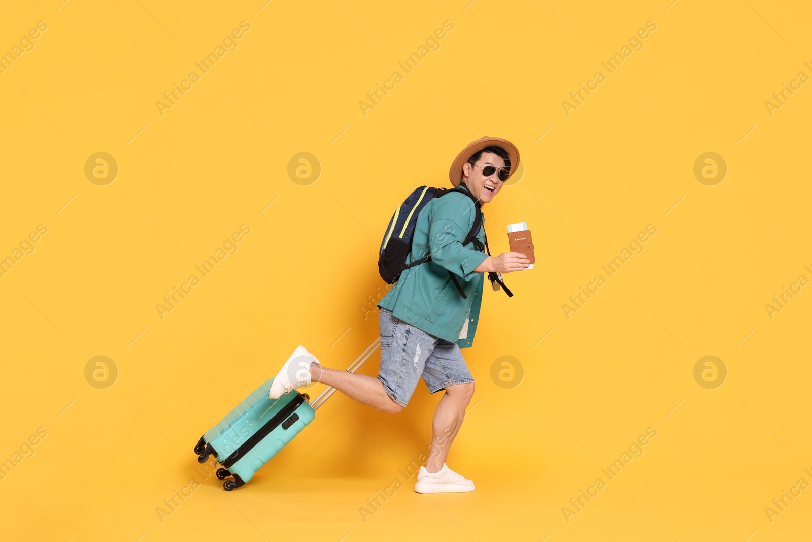 Photo of Traveller with passport and suitcase running on yellow background