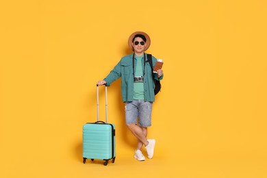 Photo of Traveller with passport and suitcase on yellow background