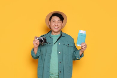 Photo of Happy traveller with passport and camera on yellow background