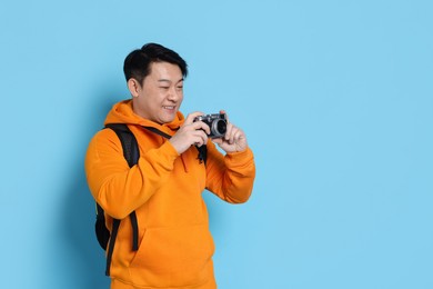 Photo of Traveller taking photo on light blue background. Space for text