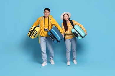 Photo of Happy travellers carrying suitcases on light blue background