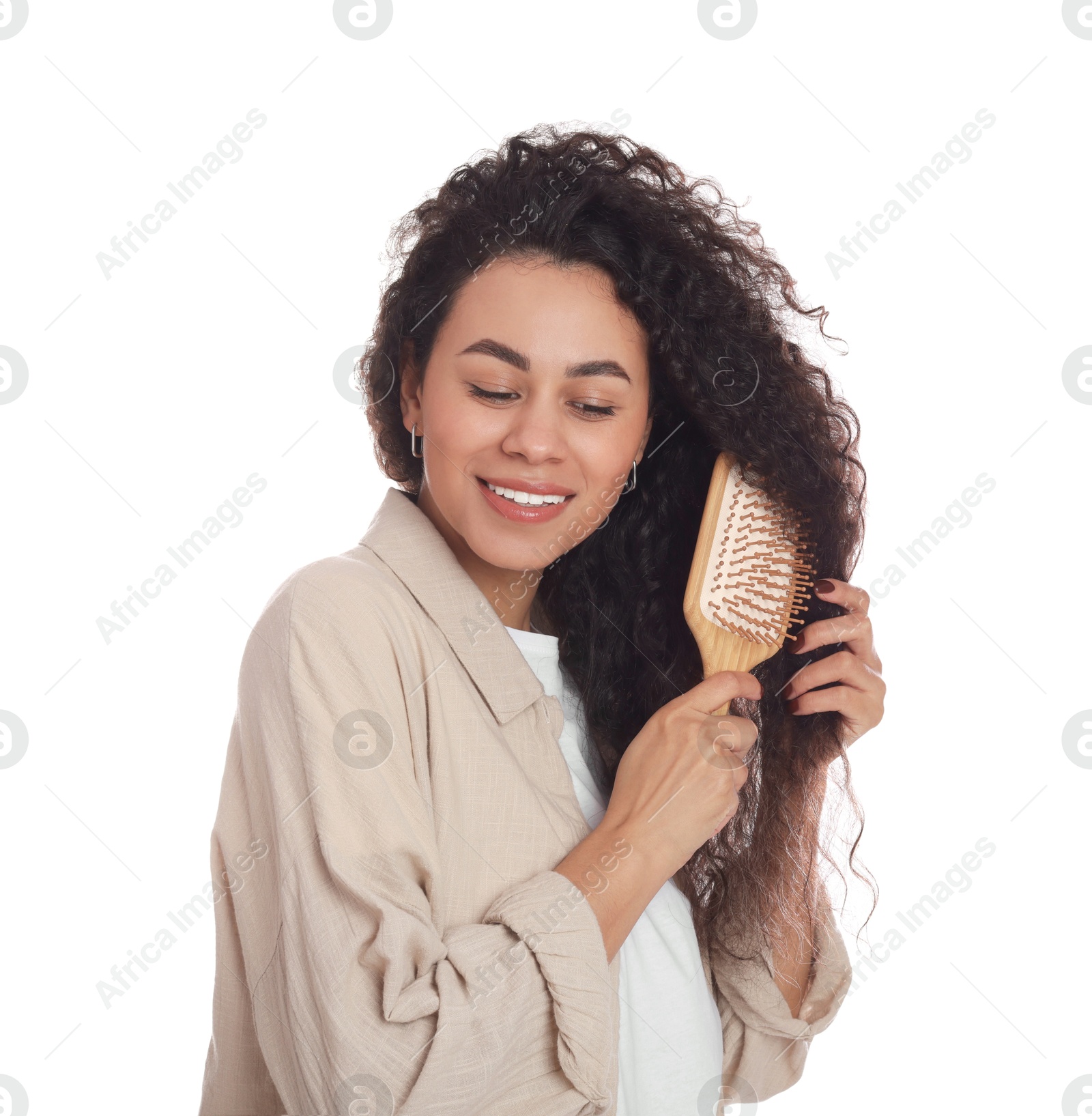 Photo of Smiling young woman brushing her curly hair on white background