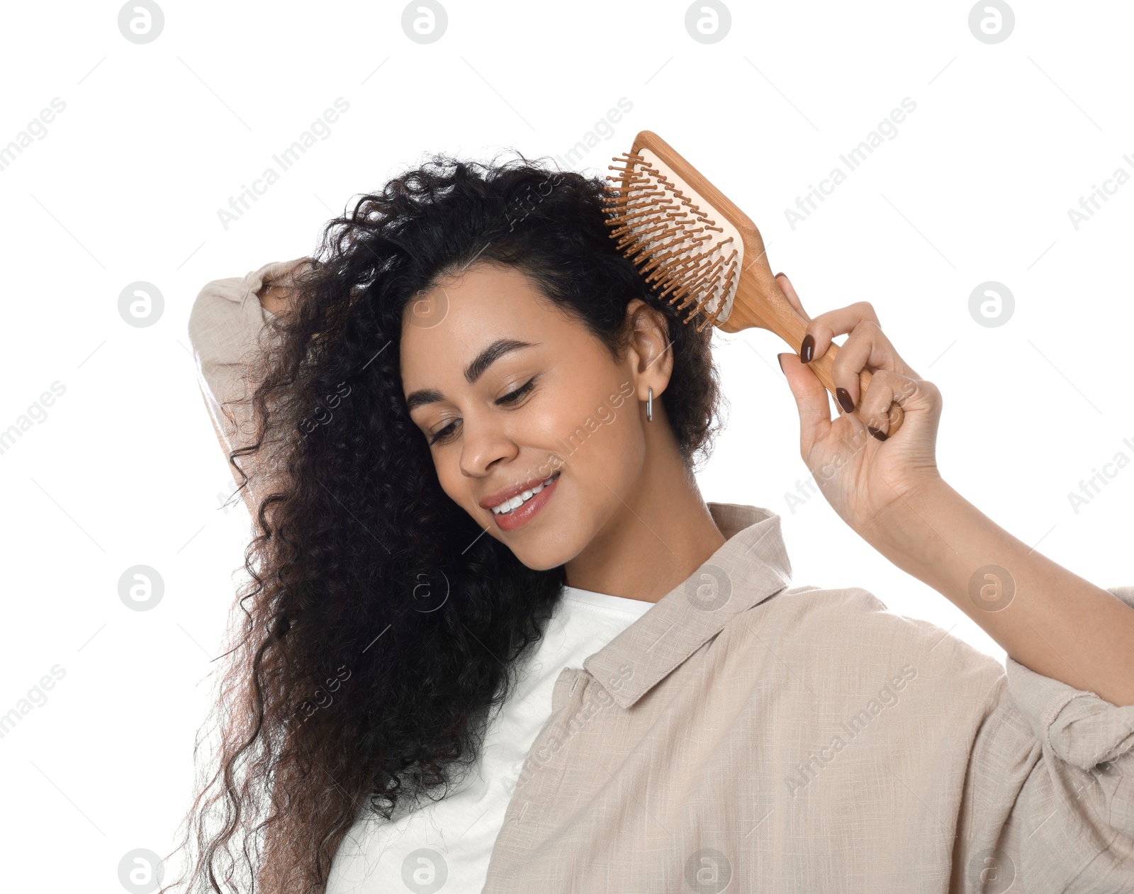 Photo of Smiling young woman brushing her curly hair on white background