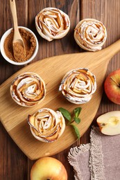 Photo of Tasty apple roses with powdered sugar served on wooden table, flat lay