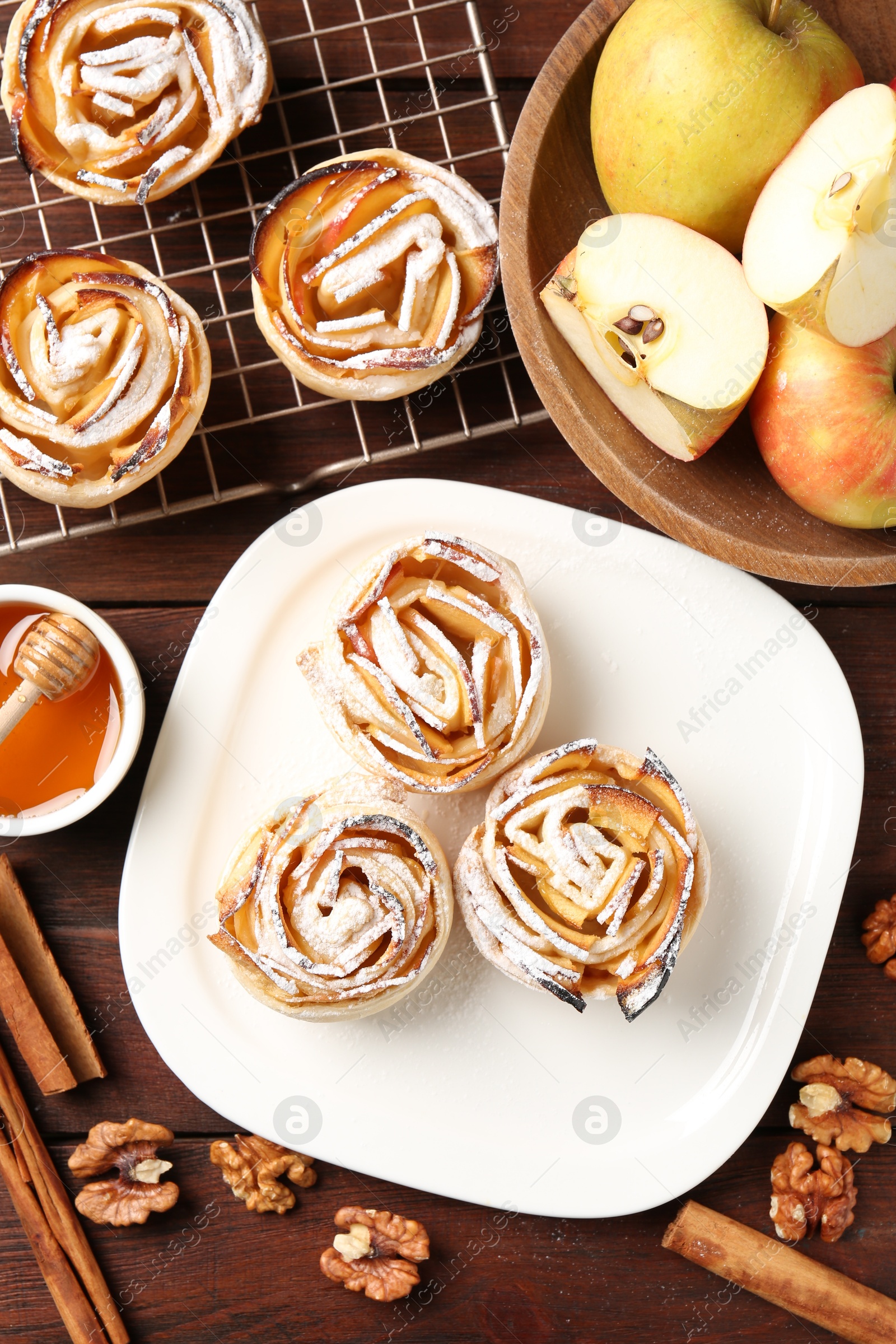Tasty apple roses with powdered sugar served on wooden table, flat lay Photo of Tasty apple roses with powdered sugar served on wooden table, flat lay