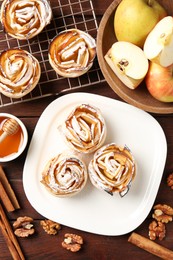Photo of Tasty apple roses with powdered sugar served on wooden table, flat lay