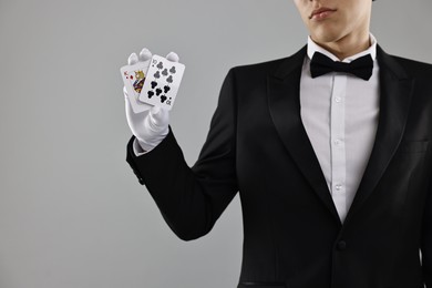 Photo of Illusionist showing playing cards on grey background, closeup. Space for text