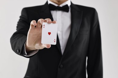 Photo of Illusionist showing playing card on white background, closeup