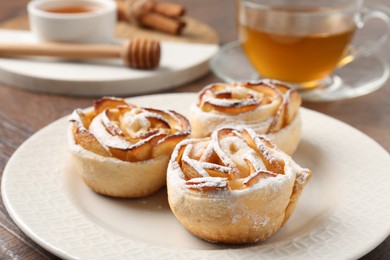Photo of Freshly baked apple roses, honey and tea on table, closeup