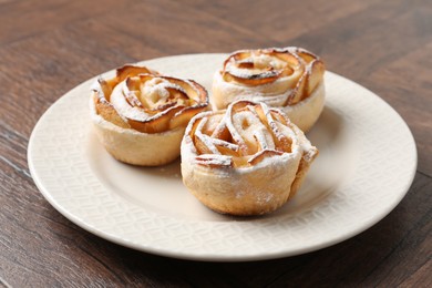 Photo of Freshly baked apple roses on wooden table, closeup