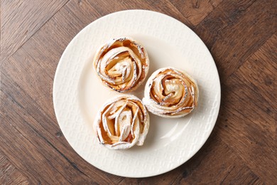 Photo of Freshly baked apple roses on wooden table, top view