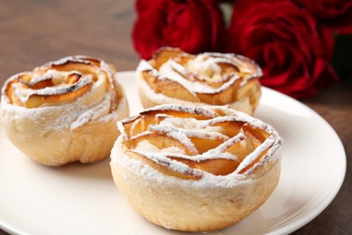 Photo of Freshly baked apple roses and beautiful flowers on table, closeup