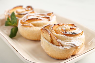 Photo of Freshly baked apple roses with mint on white table, closeup