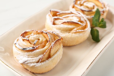 Photo of Freshly baked apple roses with mint on white table, closeup