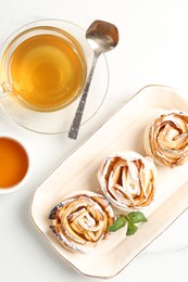 Photo of Freshly baked apple roses with mint, honey and tea on white marble table, flat lay