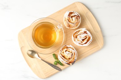 Photo of Freshly baked apple roses with mint and tea on white marble table, top view