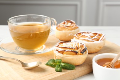 Photo of Freshly baked apple roses with mint, honey and tea on table, closeup