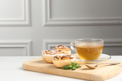 Photo of Freshly baked apple roses with mint and tea on white marble table, closeup