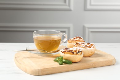Photo of Freshly baked apple roses with mint and tea on white marble table, closeup