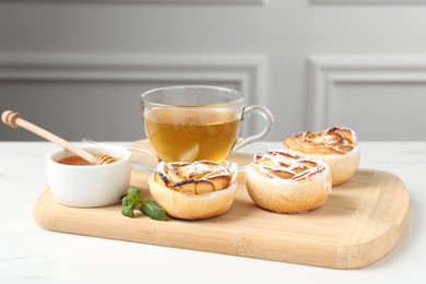 Photo of Freshly baked apple roses with mint, honey and tea on white table