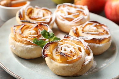 Photo of Freshly baked apple roses with mint on table, closeup