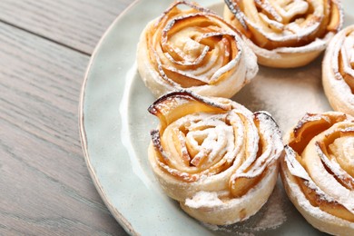 Photo of Freshly baked apple roses on wooden table, closeup