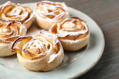 Photo of Freshly baked apple roses on wooden table, closeup