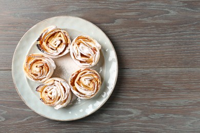 Photo of Freshly baked apple roses on wooden table, top view. Space for text