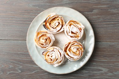 Photo of Freshly baked apple roses on wooden table, top view