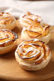 Photo of Freshly baked apple roses on wooden board, closeup