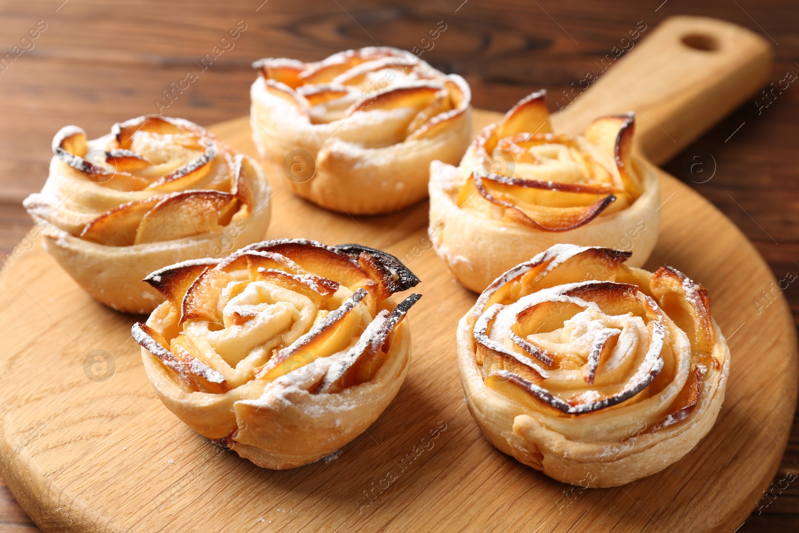Photo of Freshly baked apple roses on table, closeup
