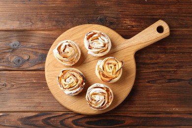 Photo of Freshly baked apple roses on wooden table, top view