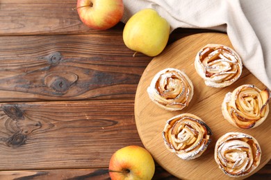 Photo of Freshly baked apple roses and fruits on wooden table, flat lay. Space for text