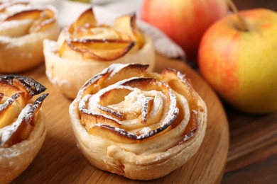 Photo of Freshly baked apple roses and fruits on table, closeup