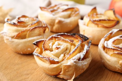Photo of Freshly baked apple roses on wooden table, closeup