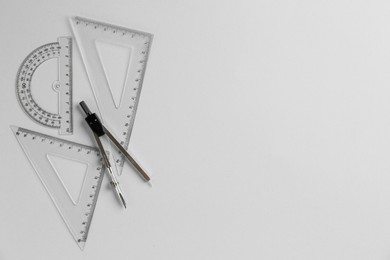 Photo of Rulers and compass on light grey background, flat lay. Space for text