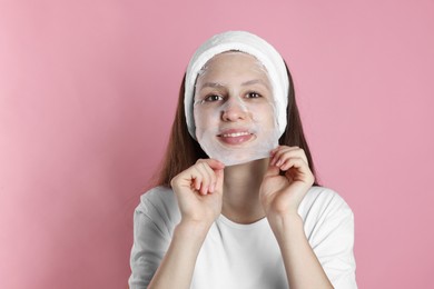 Photo of Teenage girl removing sheet facial mask on pink background. Acne treatment